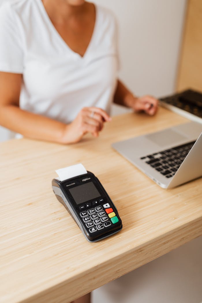 services-06 A cashier processes a cashless transaction using a payment terminal and laptop at a retail counter.